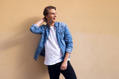 Rahat ve yakışıklı. Uzak gülümseme ile seyir ve saç sarı arka plana karşı duran el tutmak yakışıklı genç adam