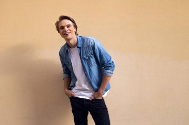 Sadece şuna yakışıklı olmuşsun. Ceplerinde duran sarı arka plana karşı gülümseyerek kameraya bakarak ve tutmak yakışıklı genç eller