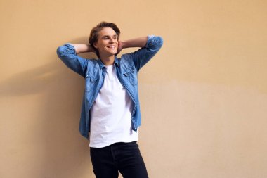 Daha yeni harika görünmesi için geç. Uzak gülümseme ile seyir ve elinde duran sarı arka plana karşı kafa tutmak yakışıklı genç adam