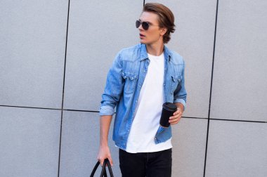 Kahve ve stil. Kahve fincanı tutarak ve uzak açık havada yürürken seyir yakışıklı genç adam