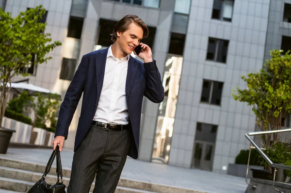 Beş dakika sonra görüşürüz. Onun çantası taşıyan ve açık havada duran ise onun smartphone kullanarak yakışıklı delikanlı