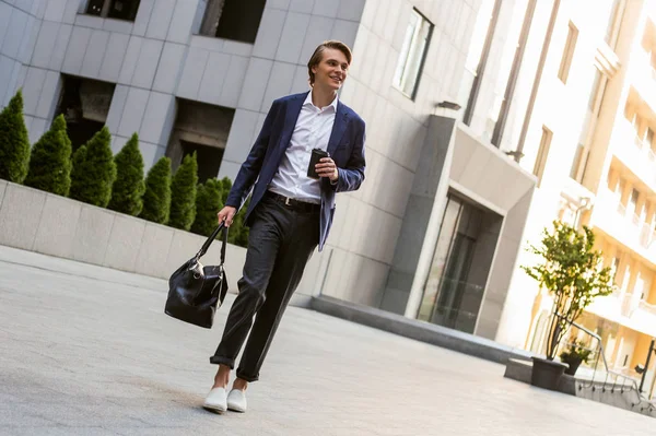 Büyük bir şehirde kahve molası. Yakışıklı genç adam onun çanta taşıyor ve kahve fincanı açık havada süre ayakta tutan