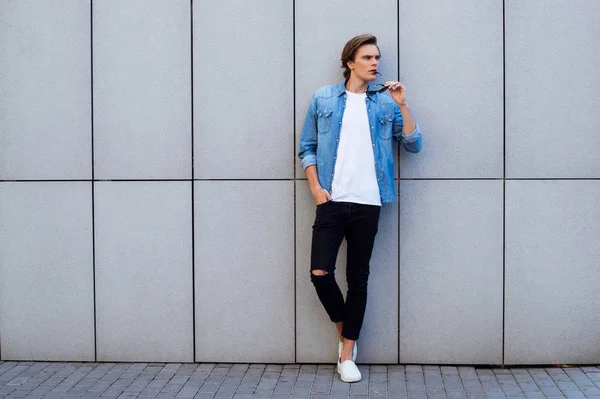 Hmmm what is going on? Full length of handsome young man carrying his sunglasses and looking away while standing outdoors