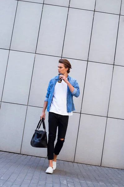 Stiline adım. Kahve fincanı tutarak ve uzak açık havada yürürken seyir yakışıklı genç adam