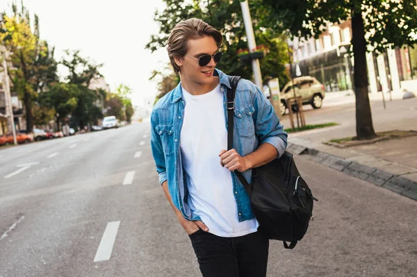 Basit görünüm. Yakışıklı genç adam uzakta açık havada gülümseme ile yürürken arıyorsunuz 