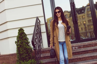 Bugün dışarı çıkacak. Güzel genç kadın kahve fincanı tutarak ve uzakta ayakta açık havada süre gülümseme ile seyir açmada