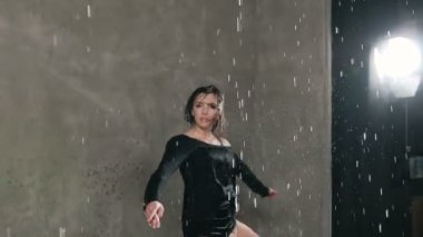 Dans dansçı kadın Studio stüdyo ışık önce su damlaları altında ıslak. Yağmur, ıslak kız dansçı siyah giysili kendini ve kamera arıyor etrafında çember yapar.