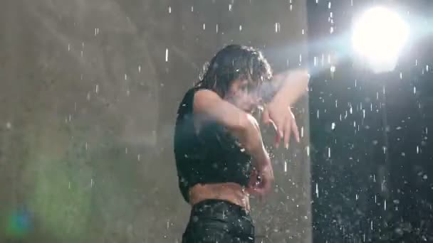 Wet girl exécute la danse contemporaine sous la pluie de l'eau sur la scène avant la lumière du studio. Danse moderne — Video