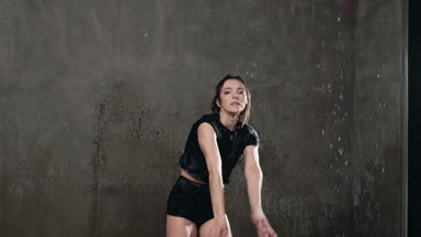 Siyah gövde ıslak kız dansçı bir sıçrama yağmur ve su sıçramalarına gerçekleştirir. Sahnede dans sırasında suyun altında dans dansçı kameraya benziyor