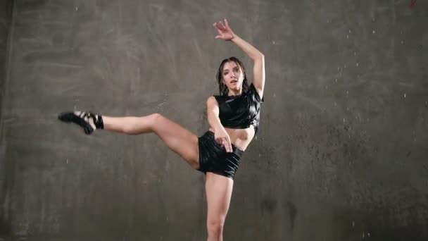 Jeune danseuse humide en body noir danse émotionnelle danse moderne sous les gouttes d'eau dans le studio en face de la lumière du studio. Entraînement danseur dansant sous des gouttelettes d'eau — Video
