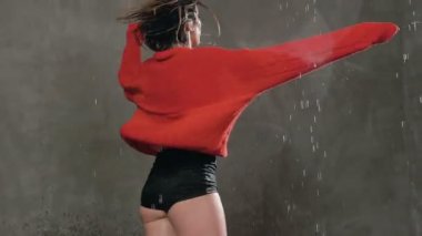 Kız dansları yağmur altında. Kırmızı kazaklı ıslak kadın dansçı kendini yağmur damlaları altında daireler. Modern dans