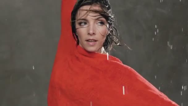 Gros plan. Jeune danseuse mouillée dansant en pull rouge et faisant des cercles autour de lui sous les gouttes d'eau dans le studio. La danse moderne. Danse sous la pluie — Video