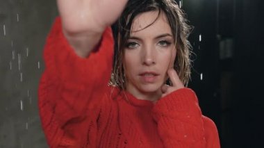 Bir kızın yakın su yağmur ıslak saç onda kırmızı kazaklı kameraya benziyor. Su damlaları altında ıslak kız kameraya doğru görünüyor. Stüdyo çekim. Portre