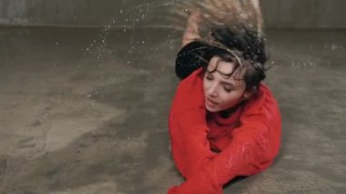 Kırmızı kazak ve siyah şort ıslak genç kadın yağmur ve su sıçramalarına altındaki katta dans ediyor. Damla su, yağmur, çağdaş dans