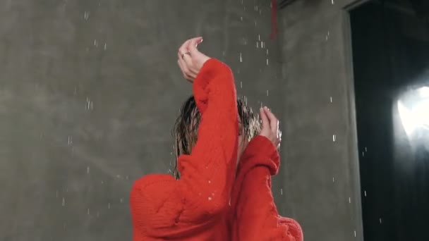 Крупный план девушки, которая смотрит в камеру у нее влажные волосы от водяного дождя. Мокрая девушка танцует современный танец и смотрит в камеру. Промокшая девочка под каплями воды смотрит в камеру — стоковое видео