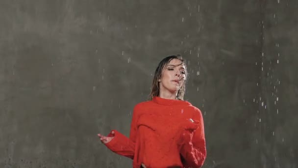 Moderner Tanz. nasse Tänzerin dreht sich im Studio unter dem Regenwasser um sich selbst, bevor leichte Tänzerinnen im roten Pullover unter den Tropfen des Wasserregens zeitgenössischen Tanz aufführen — Stockvideo