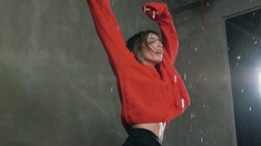 Islak genç kadın dans stüdyosu studio ışık önce yağmur suyu altında pratiği yapıyor. Egzersiz o genç kızın kapalı damla yağmur altında. Genç bir kız dans ederken bir sıçrama yapar
