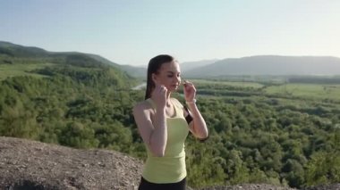 Açık havada egzersiz fitness izci Giyilebilir teknoloji dağda çalıştıran runner genç kadın. Gün batımı kulaklık ile müzik dinleme çalışan kadın atlet