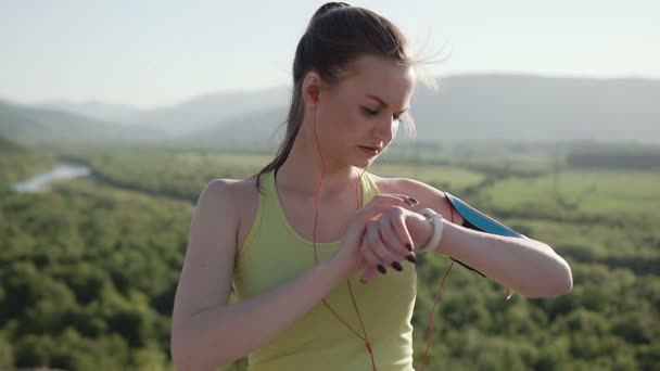 Mladý sportovní dívka ve sportu nosit, který běží na čerstvém vzduchu v horách v západu slunce poslechu hudby pomocí sluchátek ze svého smartphonu. Zdravý životní styl. Detailní záběr — Stock video