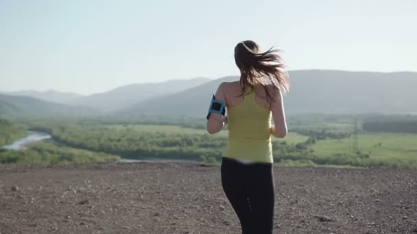 Mladá žena fitness běžec na horní šťastný a slaví úspěch. Kamera sleduje Atletika mladé ženy, která běží na vrcholu hory, vyvolává ruce do vzduchu. Zdravý životní styl — Stock video
