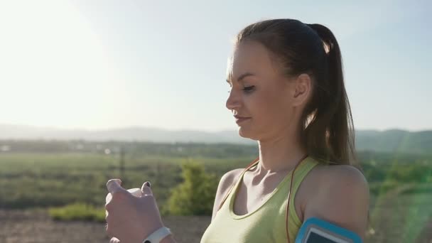 Žena pije vodu po kardio trénink v lese na hoře na pozadí. Sportovní sportovec dívka pití sladké vody do lahví a těší se to venku. Portrét krásné kavkazské fitness — Stock video