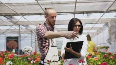 Genç kadın çiçek Bahçe için satın çiçekçi dükkanı, alışveriş müşteri olarak. Çiçek dükkanlar, kart bastırmak istemci insanlar. Sera içinde satış bahçıvan konuşurken alıcı.