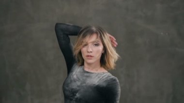 Yakın çekim. Çağdaş dans performansı solo dans toz bulutu içinde. Dans eden kız, o dans sırasında toz veya un kirli olan siyah elbise giymiş