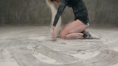 Siyah beden takım elbise giymiş dansçı kız yere çağdaş dans gerçekleştirmek, inme saçlı toz veya beyaz toz bulutu kapalı yetiştirme yapar. Beyaz pigmentler ile dans
