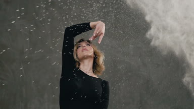 Güzel ve genç birbayan Studio sıçramalarına beyaz toz veya toz ile gri arka karşı modern dans gerçekleştirin. İçinde dans eden sevimli kız portresi kameraya ararken kapalı