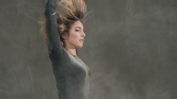 A dancer girl performs modern dance by making circles around herself in in the clouds of white powder or smoke. A woman dancing around in a black suit with splashes of flour — Stock Video