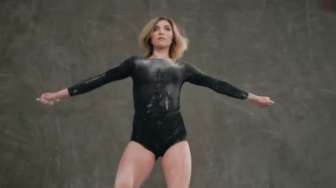 Alt görünümü. Siyah beden takım elbise giymiş bir dansçı beyaz toz veya stüdyoda gri bir duvar çerçevede bir duman bulutu içinde bir modern dans gerçekleştirmek