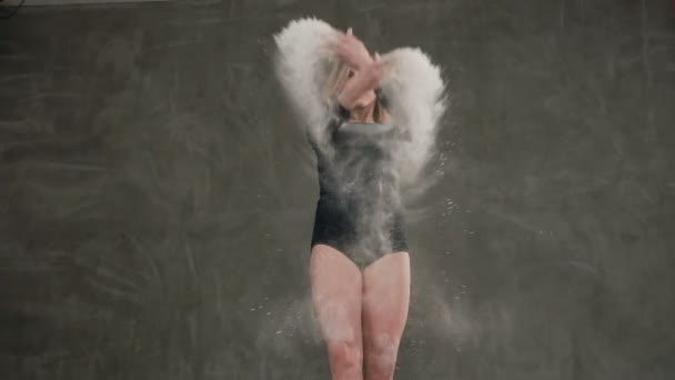 하단 보기 백색 분말 또는 배경에서 회색 벽으로 연기의 구름에서 현대 무용을 수행 백색 분말 클라우드 댄서 블랙 바디 슈트를 입은 날씬한 여자 금발 댄스는 — 비디오