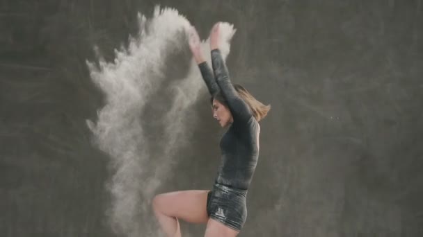 黒のボディー スーツの女性バレエ ダンサー劇場で白色の粉末または白い煙塵を使用してステージ上で実行します。ダンサー若い女性ダンス スタジオの灰色の背景に — ストック動画