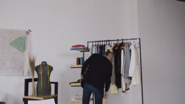 Teyp-hatta onu boyun ayakta terzilik studio ve kağıt silah çeken bir desen ile genç erkek Tasarımcısı. Erkek beyaz moda tasarımcısı ve gelecek için bir desen atelier kesmek terzi