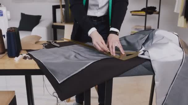 在他的工作室工作的男人裁缝的手, 在织物上画模板。裁缝在纸巾上用肥皂画线的创造性工作 — 图库视频影像