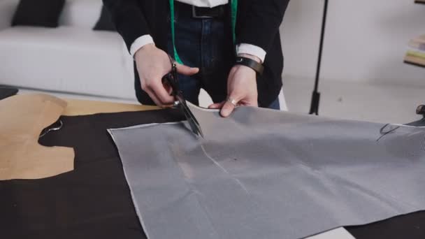 A tailor cutting a high quality fabric gray, before you sew it and make a piece of high fashion clothing. The tailor or fashion designer uses professional scissors — Stock Video