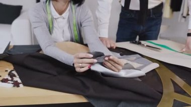 Moda tasarımcıları farklı terzilik araçları ve giysileri ile ofiste kumaş seçimi iki kişi. Genç kadın ve erkek moda tasarımcıları veya çalışma terziler gri kumaş oturma