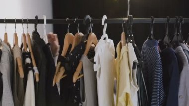 Genç esmer kadın giyim askıları üzerine bir demiryolu üzerinden seyir gözlük. Beyaz kadın giysiler bir raf üzerinde bir galeride seçmek