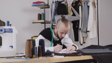 İki moda tasarımcıları onların yeni koleksiyonu için çalışma. Moda tasarımcıları birkaç atölyesinde çalışıyor. Şık sakallı adam çoğu yeni elbise koleksiyonu oluşturma sürecinde
