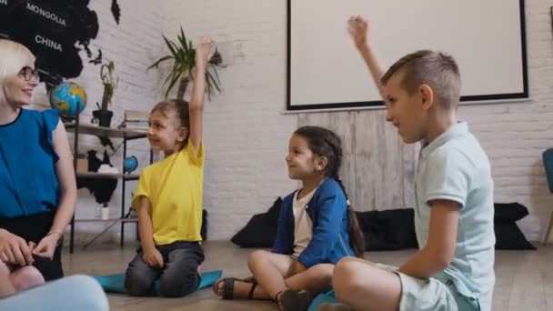 Μια ομάδα παιδιών του δημοτικού σχολείου σηκώνουν τα χέρια τους να απαντήσει η δασκάλα s διασκέδαση ερώτηση. Ομάδα των μαθητών με τα χέρια ψηλά στην τάξη κατά τη διάρκεια ένα ενδιαφέρον μάθημα από την ιστορία ή γεωγραφία — Αρχείο Βίντεο