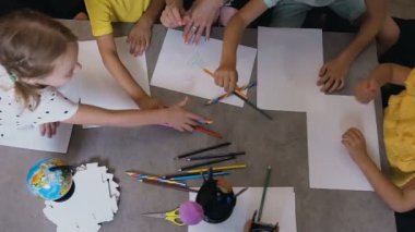 Üstten görünüm, bir grup İlköğretim Okulu Anaokulu çocuk kalem alarak çizmek çizimler bir öğretmenle ders çizim sınıf