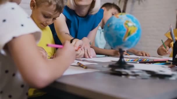 Δημοτικό σχολείο ή σχέδιο στην τάξη με καθηγητή βοηθώντας τα παιδιά του νηπιαγωγείου. Πορτρέτο του ένα νεαρό Καυκάσιος δάσκαλος που διδάσκει σχέδιο τους μαθητές κατά τη διάρκεια μαθημάτων σχεδίασης — Αρχείο Βίντεο