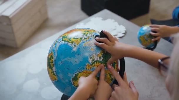 Vue de dessus. Une femme blonde discutant sur un globe avec les enfants à l'intérieur. Enseignant avec des élèves qui discutent sur un globe lors d'une leçon de géographie à l'école — Video