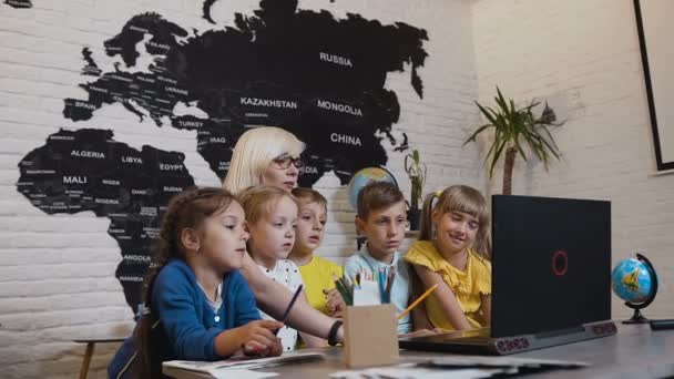 Jonge vrouw leraar met een groep leerlingen een computerprogramma te bespreken. Vrouwelijke leraar laptop met leerlingen in de klas — Stockvideo