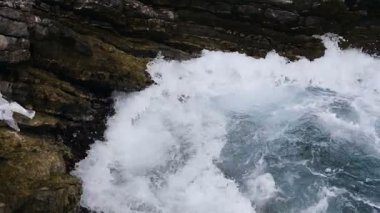 Güzel mavi deniz dalgaları kayalar ve uçurum karşı güneşli Budva, Karadağ için gürültüyle çarpmak. Köpük dalgalar. Fırtınalı deniz kıyısı. Adriyatik Denizi