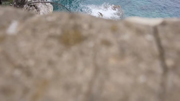 Ansicht von oben. Blick auf das kristallklare Meer, geschichtete Felsen und schöne Natur in Budva, Montenegro. azurblaues Meer, die Meereswellen schlagen gegen die Felsen — Stockvideo