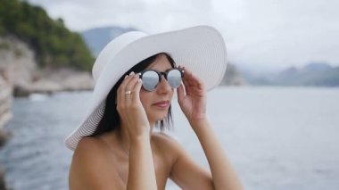 Bir kız yüz tatil portresi. Şirin kız güneş gözlüğü ve şapka sahilde. Denizde tatil. Yaz tatili