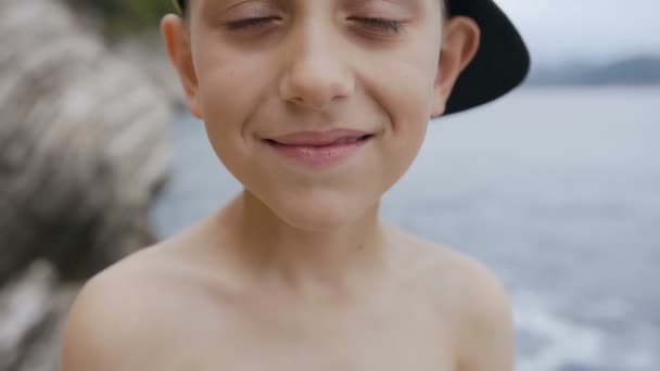정점에서 귀여운 소년의 초상화는 카메라 보고 모자. 사랑 스러운 행복 보 옥외에 카메라 보고 7-8 년의 클로즈업 — 비디오