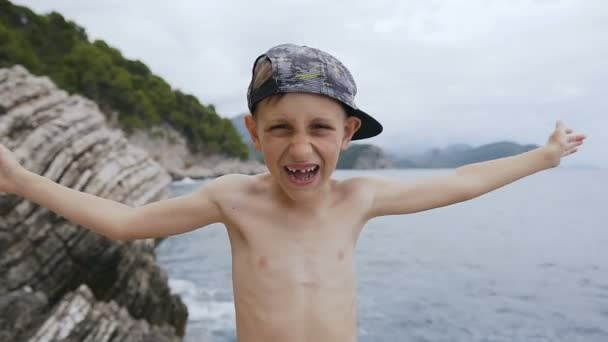 닫는 어린 소년 그의 손으로 그의 눈을 발견 하 고. 바다 배경 모자에 행복 한 아이의 초상화 — 비디오