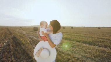 Sarı bir alan gün batımını yaz ile saman balya duran küçük oğlu olan çekici esmer. Sevgi ve hassasiyet içinde yürürken onu bebek çocuk kucaklayan bir kadın portresi